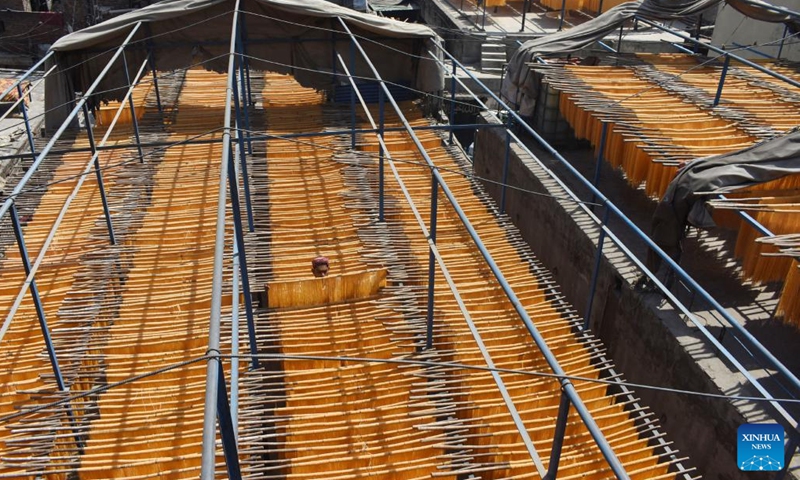 A worker hangs dried noodles at a local noodle factory in Lahore, Pakistan on April 12, 2023. Many Pakistani people buy dried noodles for an early morning meal before they start fasting during the holy month of Ramadan.(Photo: Xinhua)
