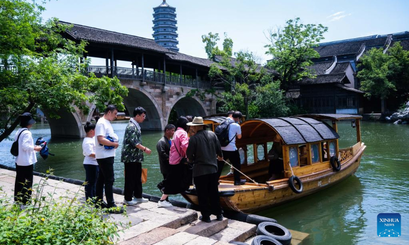 Tourists get on a boat at Puyuan Fashion Resort in Puyuan Town of Tongxiang City, east China's Zhejiang Province, May 2, 2023. (Xinhua/Xu Yu)