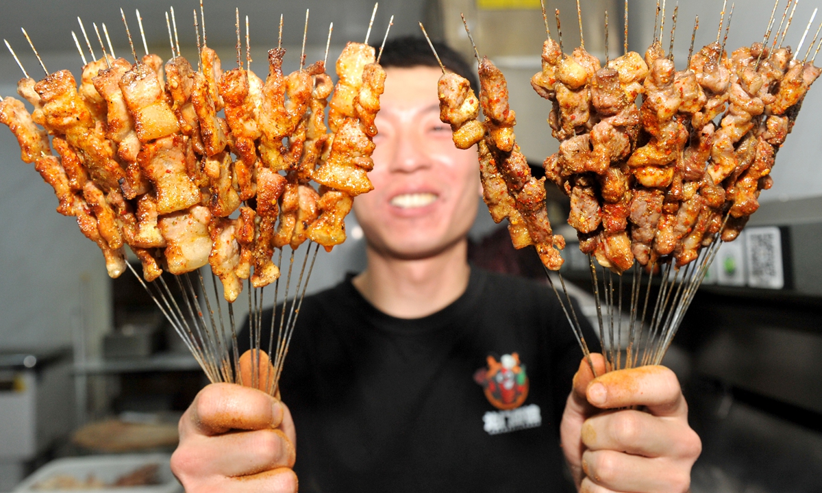 An owner of a barbecue restaurant shows the grilled skewers. Photo: VCG