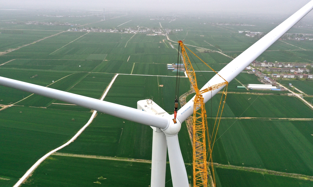 A crane hoists a turbine onto its platform at a wind farm under construction in East China's Anhui Province on April 13, 2023. China is the world's top exporter of renewable energy equipment, and its exports in 2022 helped countries reduce carbon dioxide emissions by 573 million tons, according to media reports. Photo: VCG
