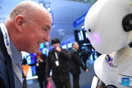 A visitor interacts with an intelligent robot at Hannover Messe 2023 in Hannover, Germany, April 19, 2023. The trade fair, one of the world's largest and lasting from April 17 to April 21, showcases more than 4,000 companies, which present solutions for the production and energy supply of the future.(Photo: Xinhua)