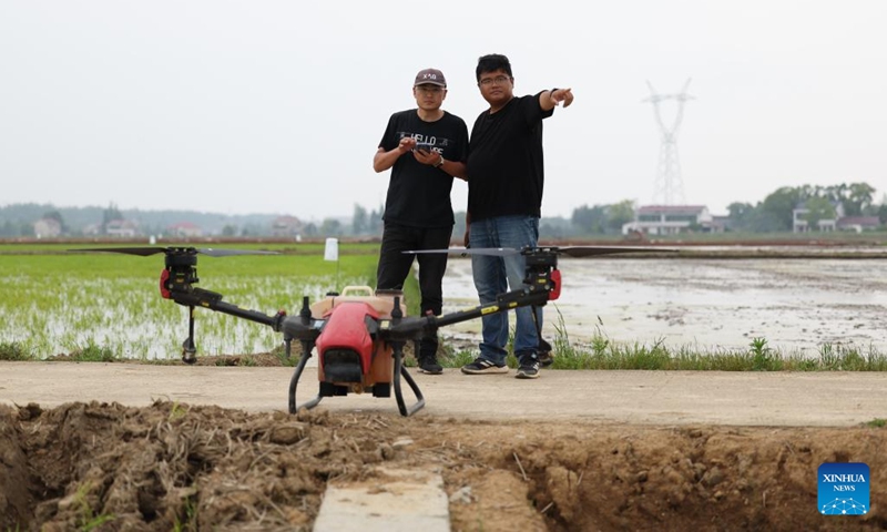 Staff members set a route for a drone to spray pesticide above a field in Zhongtang Village of Heshan District in Yiyang, central China's Hunan Province, on April 21, 2023. Agricultral machines such as rice transplanter, rotary tiller and drones have helped streamlining the spring ploughing here.(Photo: Xinhua)