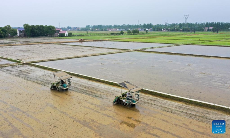 This aerial photo taken on April 21, 2023 shows farmers driving rice transplanters to transplant rice seedlings in Zhongtang Village of Heshan District in Yiyang, central China's Hunan Province. Agricultral machines such as rice transplanter, rotary tiller and drones have helped streamlining the spring ploughing here.(Photo: Xinhua)
