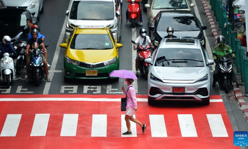 A pedestrian crosses a street with sun umbrella in Bangkok, Thailand, April 19, 2023. Thailand experienced continuous high temperature recently, with the highest temperature in many provinces exceeding 40 degrees Celsius. The Ministry of Public Health of Thailand reminded the public to reduce outdoor activities. (Photo: Xinhua)