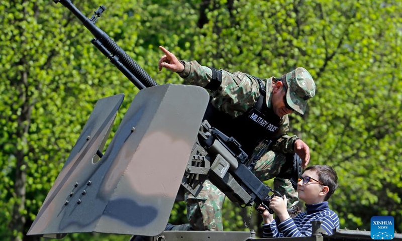 A Romanian soldier talks to a child on an armoured vehicle at a static exhibition of military equipment marking Romanian Land Forces Day at a park in Bucharest, capital of Romania, April 23, 2023.(Photo: Xinhua)