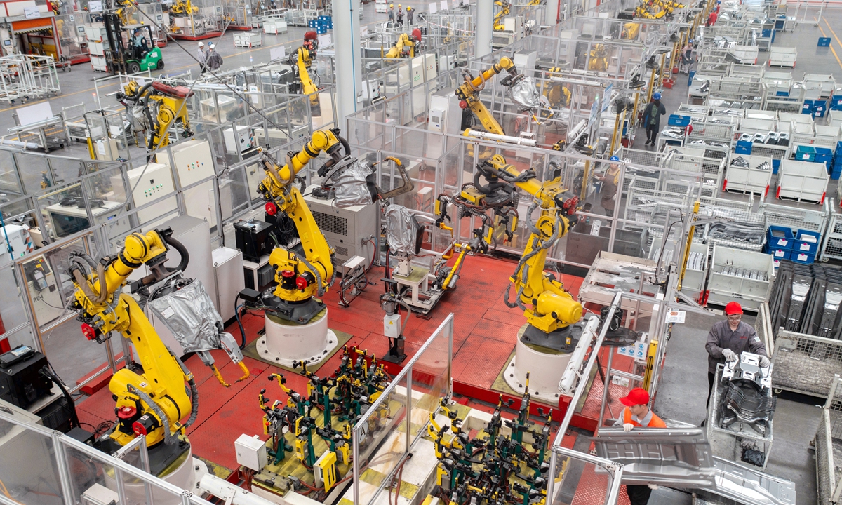 Workers and automatic robots make new-energy vehicle (NEV) parts at a factory in Huzhou, East China's Zhejiang Province, on May 4, 2023. China has been the largest NEV producer for eight years in a row. The nation produced 674,000 NEVs in March, up 44.8 percent year-on-year. Photo: VCG