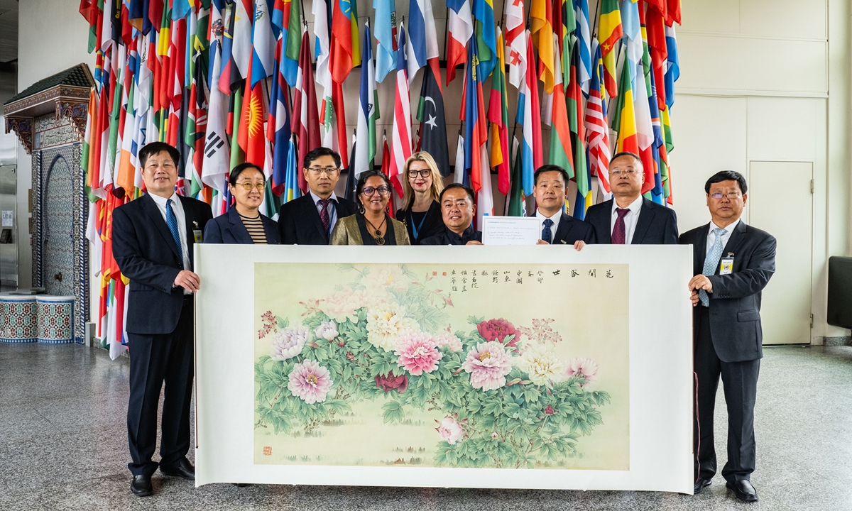 People pose for a photo with a peony painting at the 2023 UN Chinese Language Day event in Vienna, Austria, on May 2, 2023. Photo: Courtesy of Juye Painting and Calligraphy Institute 
