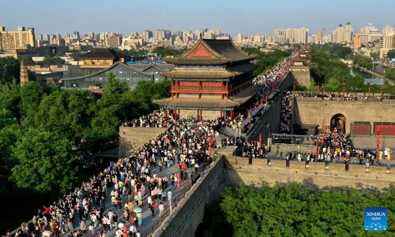 This aerial photo taken on April 30, 2023 shows tourists visiting the ancient city wall scenic spot in Xi'an, northwest China's Shaanxi Province. Xi'an, a city with over 3,100 years of history, served as the capital for 13 dynasties in Chinese history. It is also home to the world-renowned Terracotta warriors created in the Qin Dynasty (221-207 BC).(Photo: Xinhua)