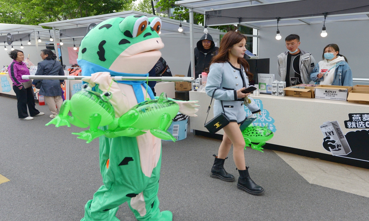 A vendor wearing a frog-shaped suit sells frog toys at a local market in Shanghai on April 23, 2023. Photo: VCG