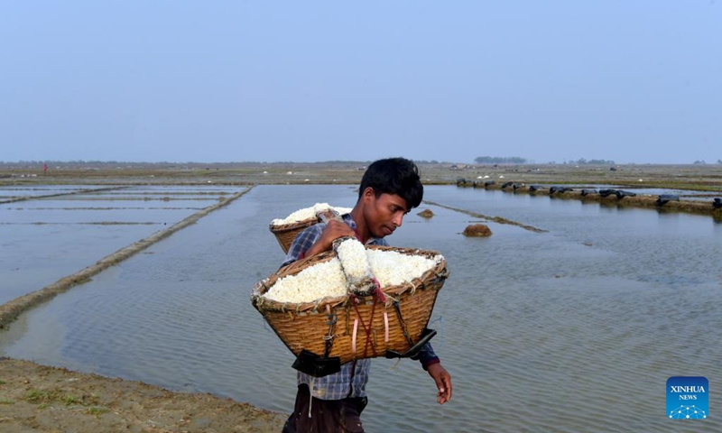 A man carries loads of sea salt in Cox's Bazar, Bangladesh on May 15, 2023. Farmers in Bangladesh's Cox's Bazar district, some 300 km southeast of capital Dhaka, are now busy harvesting salt after cyclone Mocha hit the lands(Photo: Xinhua)