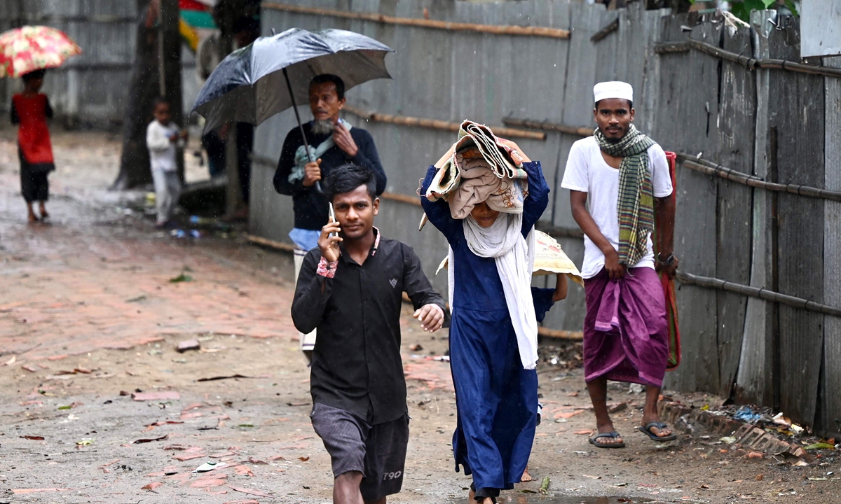 People carry their belongings to a shelter in Shahpori island on the outskirts of Teknaf, Bangladesh on May 14, 2023, ahead of Cyclone Mocha's landfall. Forecasters warned Cyclone Mocha could be the most powerful storm seen in Bangladesh in nearly two decades. About 500,000 people have been evacuated to safer areas. Photo: VCG