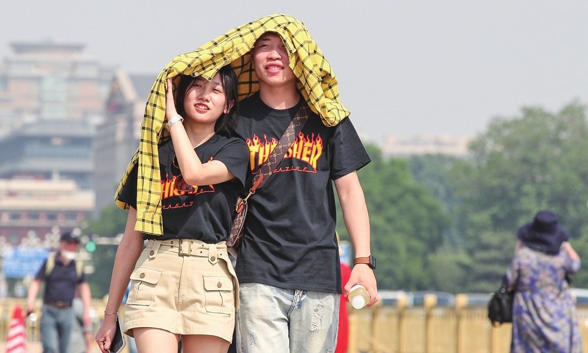 People take measures to protect themselves from the sun in Beijing on May 15, 2023. The temperature climbed to 34.4 C in the afternoon, and the Beijing meteorological observatory issued a blue warning for high temperatures. Photo: VCG