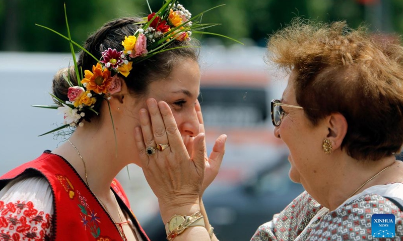 Two women interact before attending an event showcasing Romania's traditional costumes in downtown Bucharest, capital of Romania, May 14, 2023.(Photo: Xinhua)