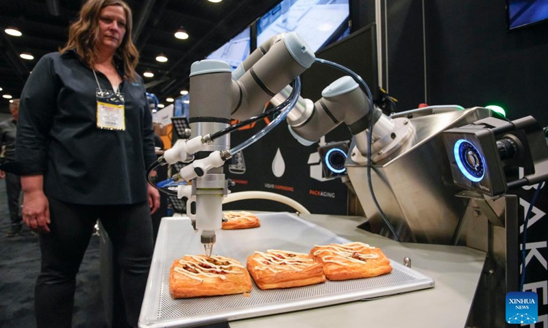 An exhibitor shows the process of bakery making by using robot arm during the Bakery Showcase 2023 held at the Vancouver Convention Center in Vancouver, British Columbia, Canada, on May 14, 2023.(Photo: Xinhua)