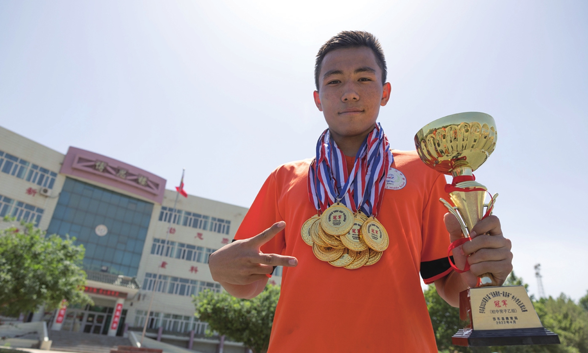 A student at the Shache County No. 2 Middle School shows off the medals and trophy his school has won on May 15, 2023.Photo: Li Hao