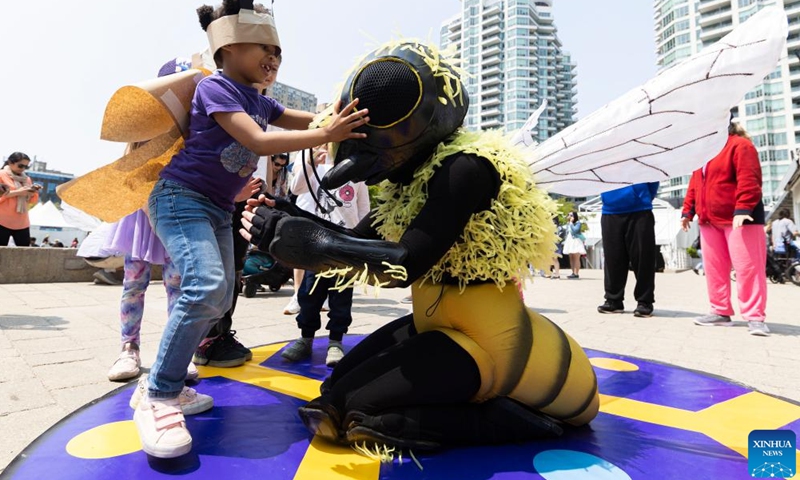 A child interacts with a performer in bee costume during the 2023 Junior International Children's Festival in Toronto, Canada, on May 21, 2023. The event is held here from May 20 to 22 to inspire children to recognize their limitless potential and learn about the world around them. (Photo by Zou Zheng/Xinhua)