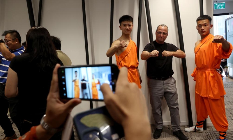 An Israeli visitor poses for a photo with Chinese martial artists during the Tea for Harmony cultural salon at the China Cultural Center in Tel Aviv, Israel, on May 21, 2023. A cultural salon named Tea for Harmony was held here on Sunday. Several booths were set up for participants to taste different kinds of Chinese tea, in addition to dances and Wushu demonstrations with performers from central China's Henan Province. (Photo by Gil Cohen Magen/Xinhua)