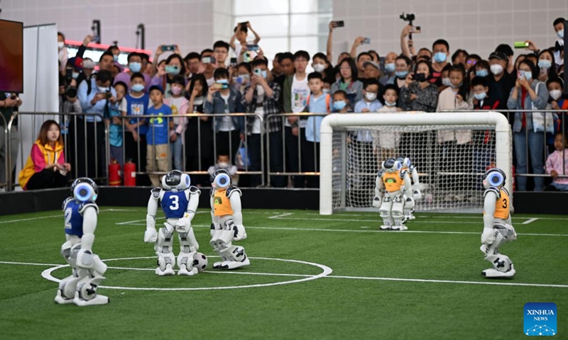 Зрители наблюдают за футбольным матчем роботов во время седьмого Всемирного конгресса разведки (WIC) в Тяньцзине на севере Китая, 20 мая 2023 года. WIC, крупное мероприятие по искусственному интеллекту (ИИ) в Китае, стартовало здесь в четверг.  (Синьхуа/Ли Ран)
