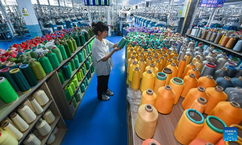 A staff member picks a roll of yarn at a workshop of a hosiery company at Datang Subdistrict of Zhuji City, east China's Zhejiang Province, May 25, 2023. Datang Subdistrict of Zhuji City is the largest hosiery production base in the world, which produces 25 billion pairs of socks every year, accounting for more than 70% of the output of China and one third of the whole world.(Photo: Xinhua)