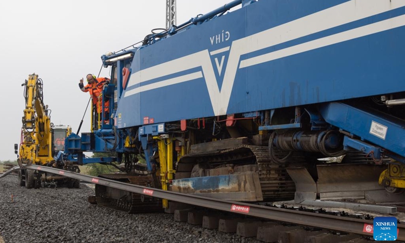 A worker operates a machine to lay a steel rail at the construction site of the Budapest-Belgrade railway in Kunszentmiklos, Hungary, on May 30, 2023. Against the backdrop of dark skies, pouring rain, thunder, and lightning, the arduous task of laying rails for the Chinese-built section in Hungary of the Budapest-Belgrade railway project got underway here on Tuesday, marking a significant milestone in the project.(Photo: Xinhua)