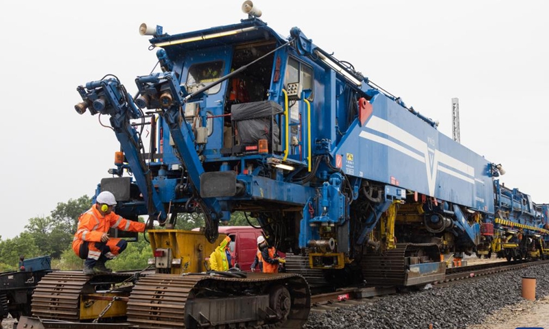 A worker checks the track laying machine at the construction site of the Budapest-Belgrade railway in Kunszentmiklos, Hungary, on May 30, 2023. Against the backdrop of dark skies, pouring rain, thunder, and lightning, the arduous task of laying rails for the Chinese-built section in Hungary of the Budapest-Belgrade railway project got underway here on Tuesday, marking a significant milestone in the project.(Photo: Xinhua)