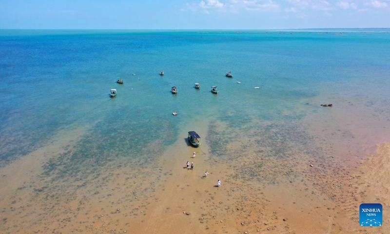 This aerial photo shows tourists having fun at Nanji Village of Jiaowei Township of Xuwen County, Zhanjiang City, south China's Guangdong Province, May 28, 2023. The village, which is surrounded by Qiongzhou Strait and Beibu Gulf, is located in Jiaowei Township of Xuwen County. In recent years, more and more tourists are attracted to visit here for its good natural environment and unique fishing village atmosphere.(Photo: Xinhua)