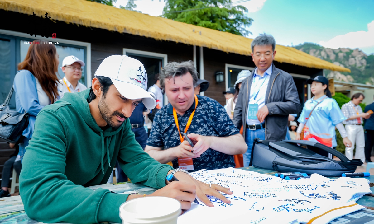 Foreign journalists sign on a T-shirt during visit at the Laoshan Mountain in Qingdao on May 23, 2023. Photo: Courtesy of Global Times Online