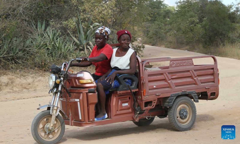 Adefi Mtambo (L) drives an e-tricycle on a dusty road in Wedza, about 140 kilometres from Zimbabwe's capital Harare, May 19, 2023.(Photo: Xinhua)
