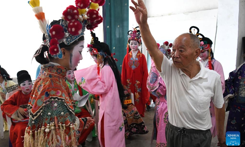 Elderly folk artist Shao Qianfeng (R, front) instructs a student before a display of Anhui Opera at Fuling Village of Jixi County, Xuancheng City, east China's Anhui Province, May 30, 2023. In order to promote Anhui Opera and raise awareness of the traditional performing art, a primary school in Fuling Village has been offering a routine training program since 2003 for its students, hiring veteran folk artists as tutors.(Photo: Xinhua)