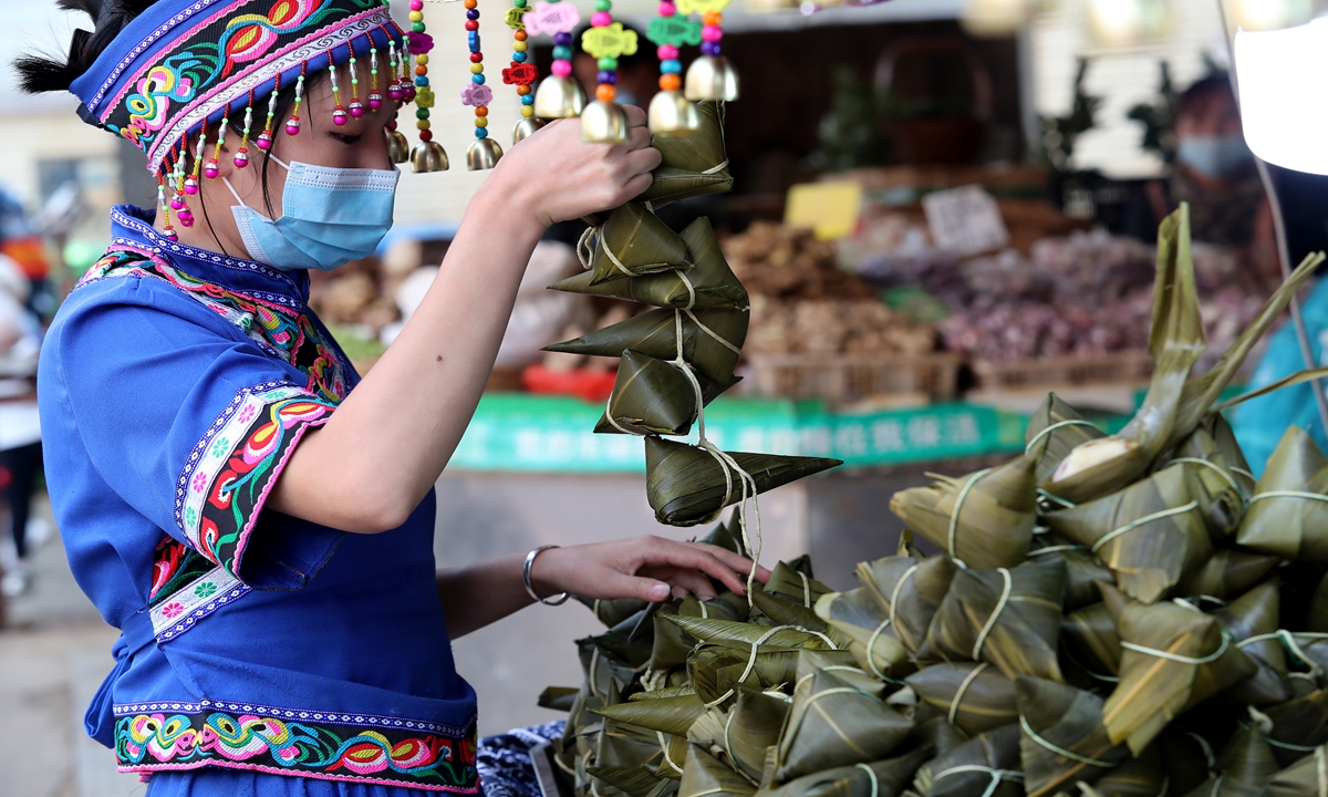 A salesperson wearing an ethnic costume packs zongzi, or traditional Chinese rice puddings, at a market in Kunming, Southwest China's Yunnan Province on June 4, 2023. As the traditional Dragon Boat Festival, which falls on June 22, approaches, a variety of zongzi - a traditional food for the festival - with different flavors have been put into the market. Photo: VCG