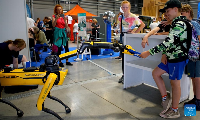 A robot hands a notebook to a boy at the Science Fair in Prague, the Czech Republic, on June 8, 2023. The Science Fair, organized annually by the Academy of Sciences of the Czech Republic, is held from June 8 to June 10 this year.(Photo: Xinhua)