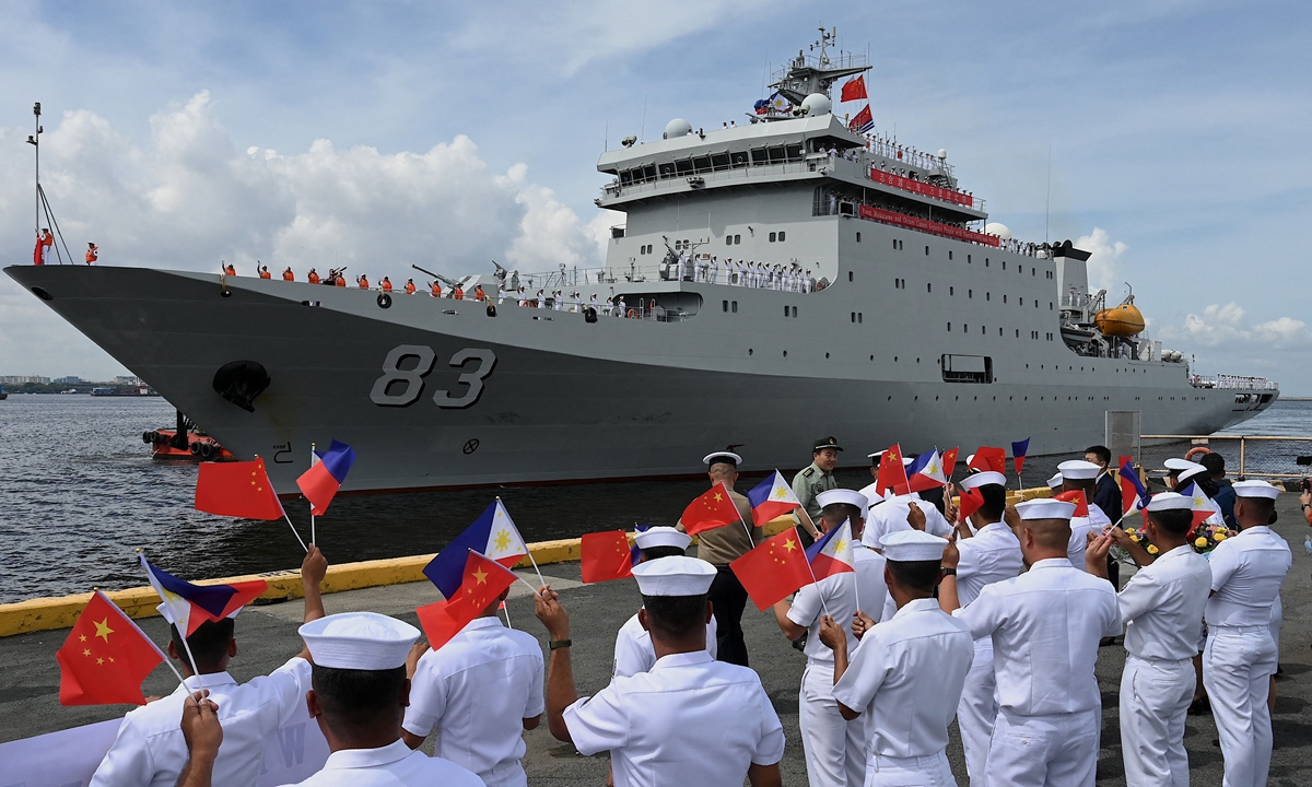Philippine Navy personnel wave flags as they welcome the arrival of the Chinese naval training ship <em>Qi Jiguang</em> in Manila on June 14, 2023. Photo: VCG