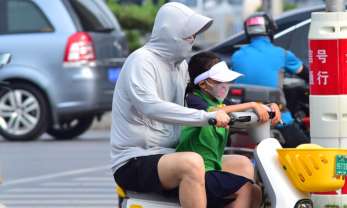 People in Shenyang travel with sun protection as the high temperature continues on June 19, 2023. Photo: VCG 