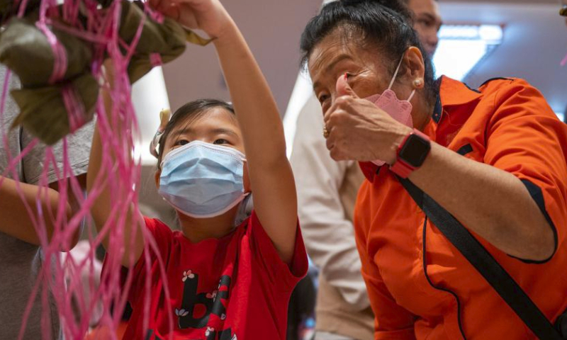 A child learns to wrap Zongzi, a pyramid-shaped glutinous rice dumpling wrapped in bamboo or reed leaves, during a contest in celebration of the upcoming Chinese Dragon Boat Festival in Kuala Lumpur, Malaysia, June 18, 2023. (Photo by Chong Voon Chung/Xinhua)