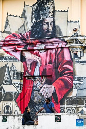 Tourists rest in front of a mural at Malacca, Malaysia, June 18, 2023. Malacca, located on the northern shore of the Strait of Malacca, is a historic city and capital of the state of Malacca.(Photo: Xinhua)