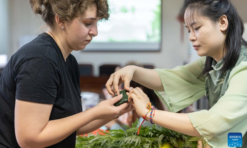 A person learns to make Zongzi, a pyramid-shaped dumpling made of glutinous rice wrapped in bamboo or reed leaves, to celebrate the Dragon Boat Festival in Vladivostok, Russia, June 22, 2023. The Confucius Institute of the Russian Far Eastern Federal University organized cultural activities on the occasion of the China's Dragon Boat Festival. (Photo by Guo Feizhou/Xinhua)