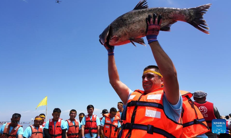 A fisherman displays a newly-caught fish at the Bosten Lake in Bohu County, northwest China's Xinjiang Uygur Autonomous Region, June 23, 2023. Photo: Xinhua