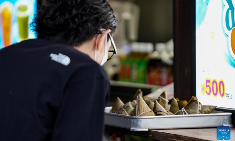 A tourist buys Zongzi, a pyramid-shaped dumpling made of glutinous rice wrapped in bamboo or reed leaves, on the occasion of Dragon Boat Festival in Chinatown of Yokohama, Japan, June 22, 2023. (Xinhua/Zhang Xiaoyu)