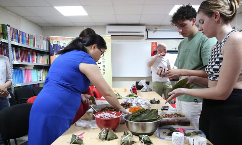 Students of the University of Malta learn to make Zongzi, a pyramid-shaped dumpling made of glutinous rice wrapped in bamboo or reed leaves, in Msida, Malta, on June 22, 2023. To celebrate the Dragon Boat Festival, the Confucius Institute at the University of Malta on Thursday organized a special event where students can participate in making and enjoying Zongzi. (Xinhua/Chen Wenxian)