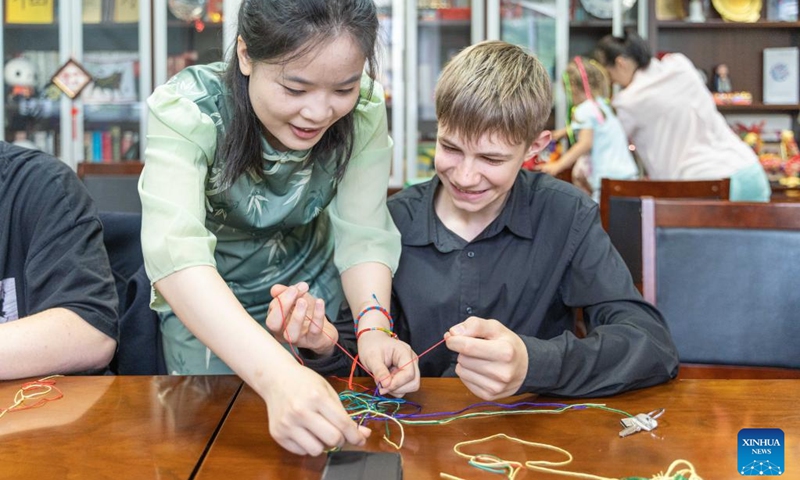 A person learns to weave colorful ropes to celebrate the Dragon Boat Festival in Vladivostok, Russia, June 22, 2023. The Confucius Institute of the Russian Far Eastern Federal University organized cultural activities on the occasion of the China's Dragon Boat Festival. (Photo by Guo Feizhou/Xinhua)