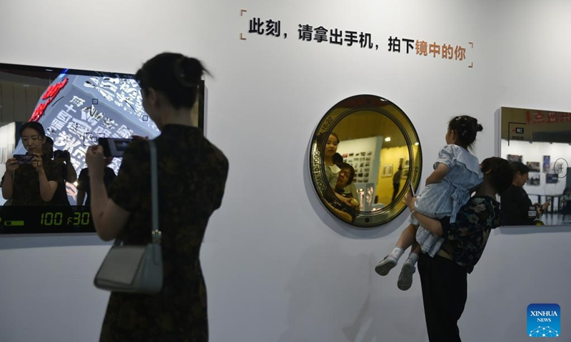 Visitors interact with an exhibit at a photography exhibition during the 14th China Photography Festival in Sanmenxia City of central China's Henan Province, June 22, 2023. (Xinhua/Lu Peng)