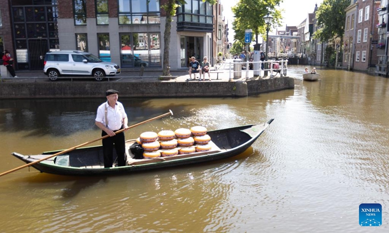 A man transports cheeses in a boat in Alkmaar, the Netherlands, on June 23, 2023. Every Friday in the small town of Alkmaar, cheesemongers sell their products at the Alkmaar cheese market. (Photo by Sylvia Lederer/Xinhua)