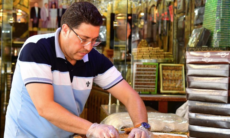 A sweet maker prepares special sweets for the upcoming Muslim festival of Eid al-Adha, or the Feast of Sacrifice, in Damascus, Syria, June 27, 2023. (Photo by Ammar Safarjalani/Xinhua)