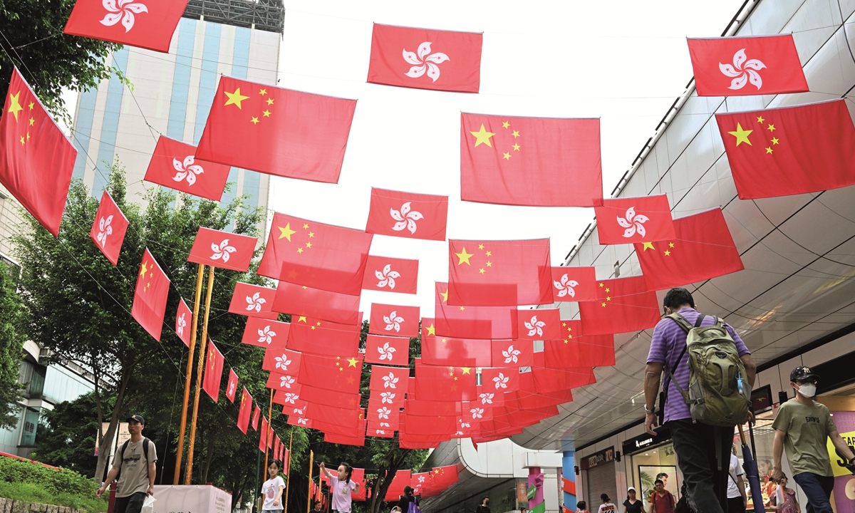 Two days ahead of the 26th anniversary of Hong Kong's return to the motherland, residents in the Hong Kong Special Administrative Region walk along the streets with Chinese national flags and Hong Kong regional flags hanging above in a festive atmosphere. Photo: VCG