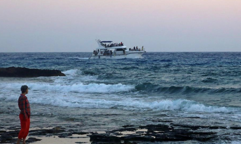 This photo taken on June 26, 2023 shows the sunset near the Bridge of Lovers at the seaside of Ayia Napa, Cyprus. The Bridge of Lovers, a natural rocky arch bridge at the seaside of Ayia Napa, has attracted many visitors. (Xinhua/Guo Mingfang)