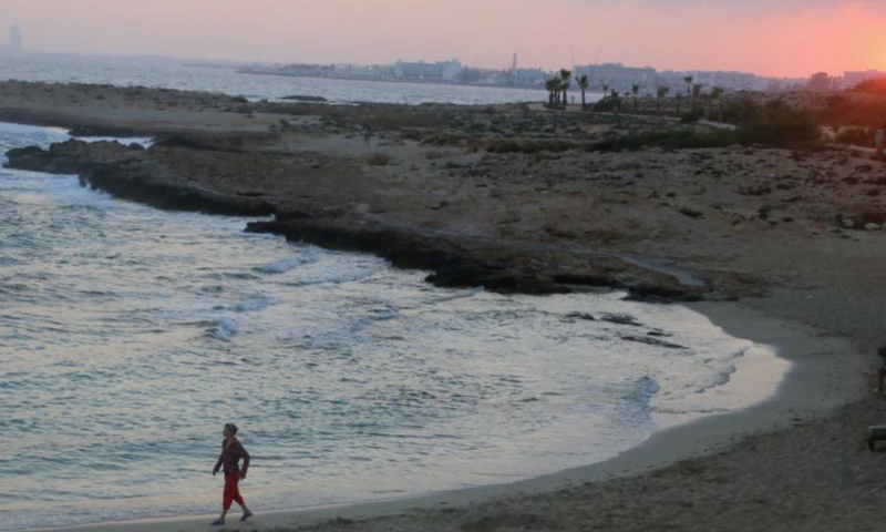 This photo taken on June 26, 2023 shows the sunset near the Bridge of Lovers at the seaside of Ayia Napa, Cyprus. The Bridge of Lovers, a natural rocky arch bridge at the seaside of Ayia Napa, has attracted many visitors. (Xinhua/Guo Mingfang)