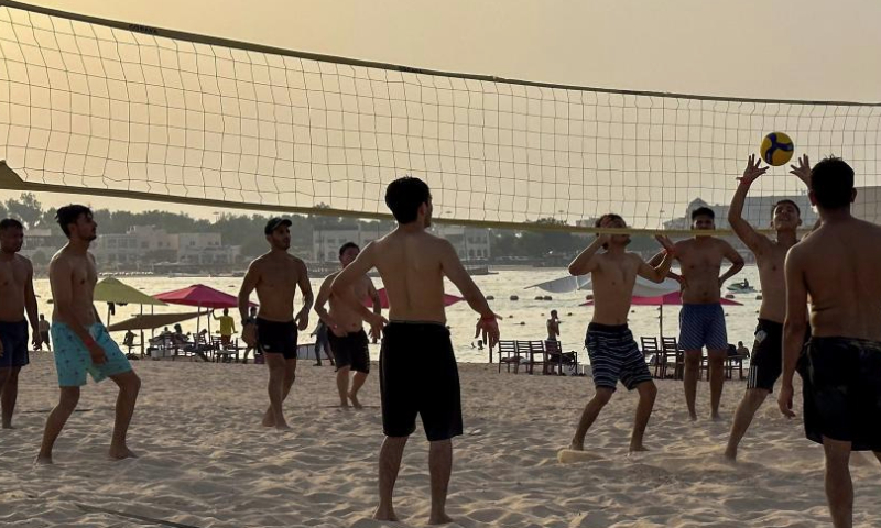 Young people play volleyball on Katara beach in Doha, Qatar, on July 7, 2023. (Photo by Nikku/Xinhua)