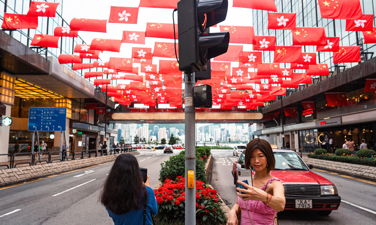 Local residents take photos of Chinese national flags and flags of Hong Kong Special Administrative Region on Friday, ahead of July 1 which marks the 26th anniversary of Hong Kong's return to the motherland. Photo:VCG