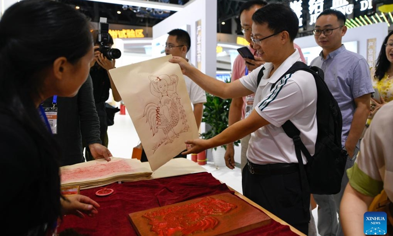 A visitor learns about Jiajiang new year painting at the Leshan exhibition area during the 19th Western China International Fair (WCIF) in Chengdu, southwest China's Sichuan Province, June 29, 2023. Kicking off here on Thursday, the five-day fair attracts more than 3,500 enterprises from 56 countries and regions.(Photo: Xinhua)