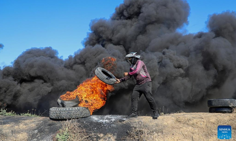A Palestinian protester burns a tire during a protest against the killing of Palestinians near the fence of the Gaza-Israel border, east of Gaza City, on July 3, 2023. At least eight Palestinians were killed and dozens were injured in the northern West Bank city of Jenin on Monday during the Israeli operation launched from midnight throughout the day, said the Palestinian Health Ministry.(Photo: Xinhua)